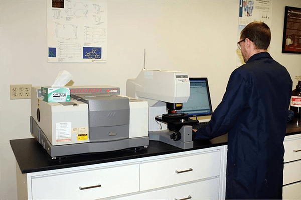 Materials testing lab technician in dark blue lab coat performing analysis