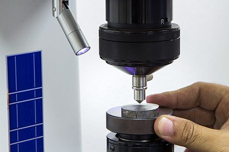 Rockwell hardness test being performed on a metal sample