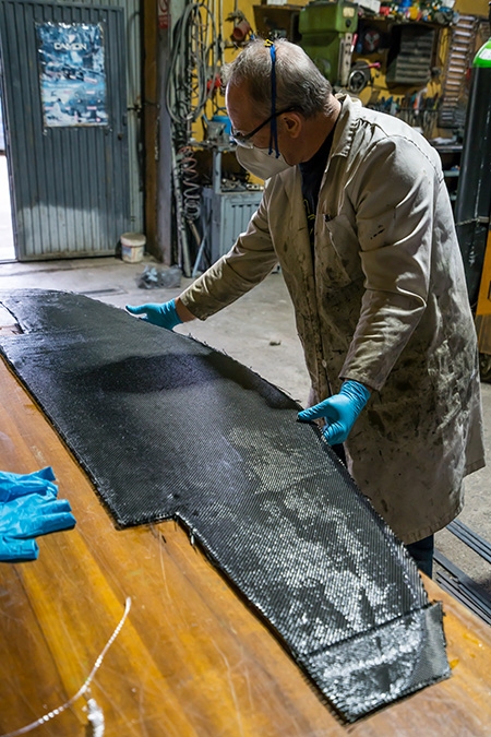 Experienced technician preparing black prepreg composite materials
