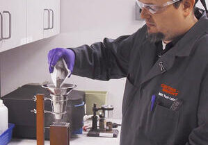 Technician pouring sample of titanium powder for tap density testing.